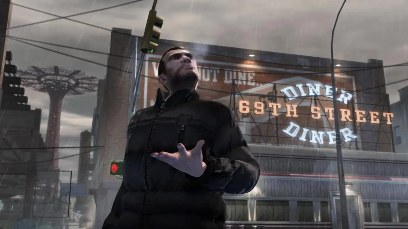 Niko Bellic en blouson noir, sous la pluie, lève les yeux devant l'enseigne du 69th Street Diner à Liberty City dans GTA IV
