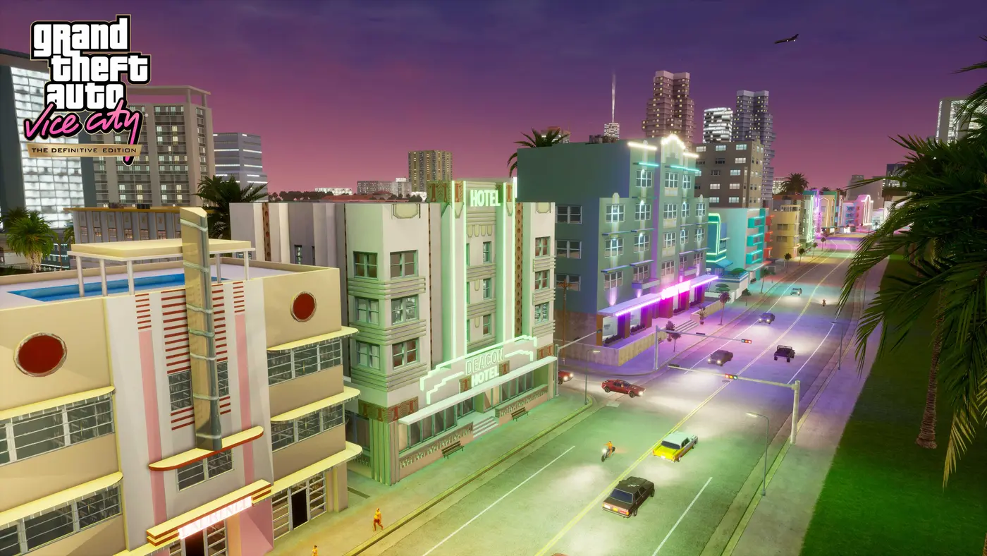 Capture officielle de GTA Vice City The Definitive Edition : l'avenue d'Ocean Beach au crépuscule, hôtels Art déco pastel aux néons verts et roses, palmiers, voitures des années 80 et ciel violet
