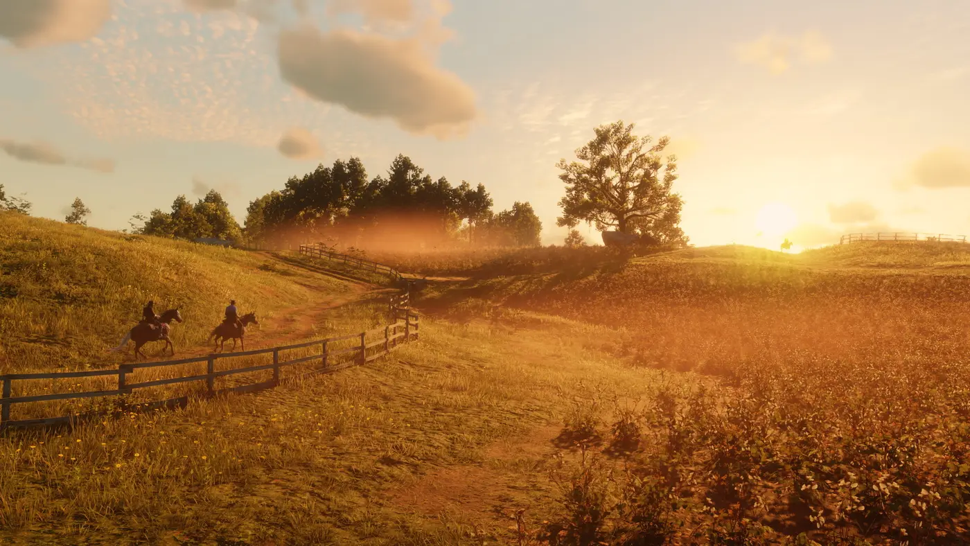 Deux cavaliers longent une clôture de bois au coucher de soleil doré, dans les plaines vallonnées de Red Dead Redemption 2, un troisième cavalier se découpant à l'horizon