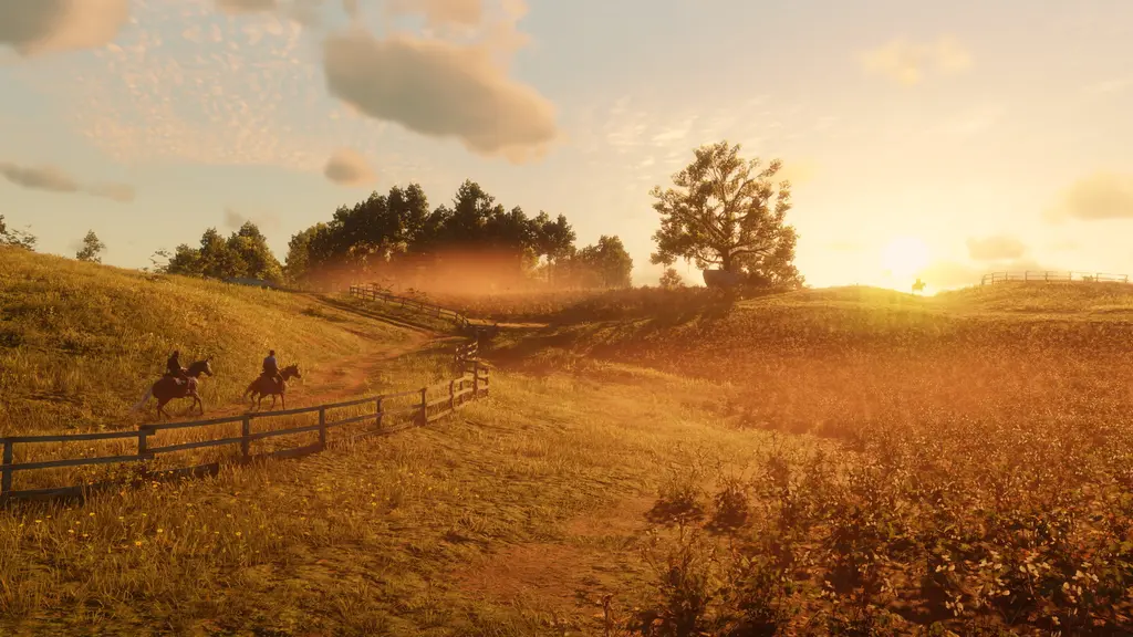 Deux cavaliers longent une clôture en bois à travers des collines herbeuses baignées par la lumière dorée du soleil couchant dans Red Dead Redemption 2
