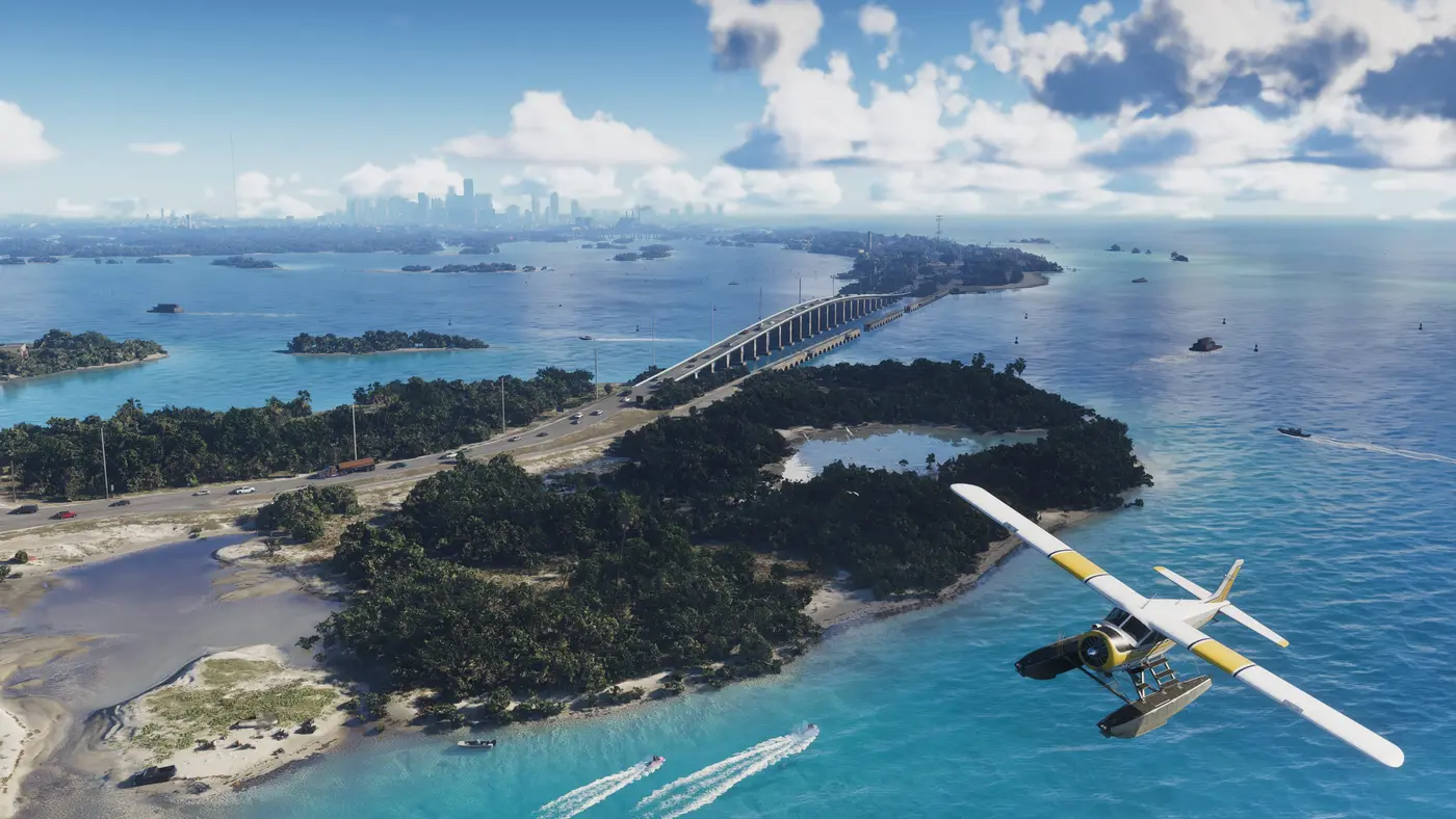 Vue aérienne diurne des Leonida Keys dans GTA VI : un hydravion jaune et blanc survole une eau turquoise, une longue digue routière relie des îlots boisés, des bateaux laissent des sillages et la skyline de Vice City se devine dans la brume à l'horizon
