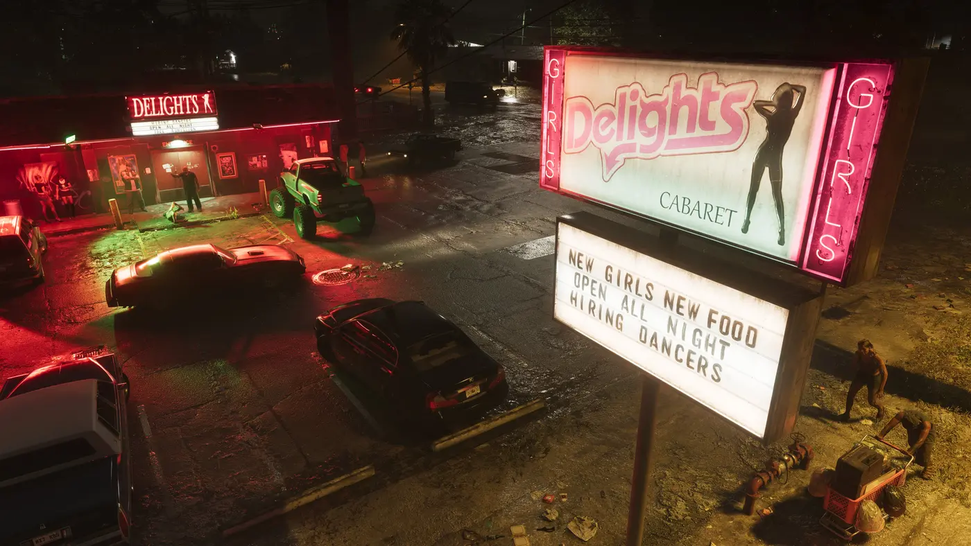 Cabaret Delights à Port Gellhorn dans GTA VI, de nuit sous une pluie fine, enseigne au néon rose, bitume mouillé reflétant les lumières, quelques voitures et PNJ dans le parking